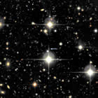 Arrow points to supernova SNLS 06D4eu and its host galaxy, both about 10 billion light-years away. Big objects with spikes are stars in our own Milky Way; every other bright dot is a distant galaxy. Credit: University of California, Santa Barbara